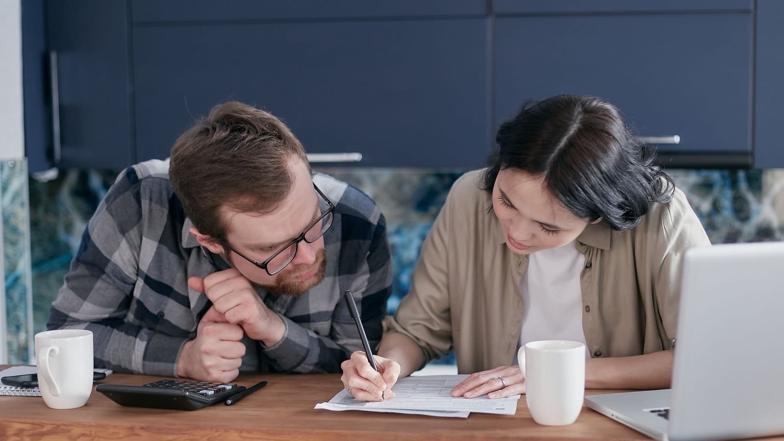 Couple filling in an application form at the kitchen table