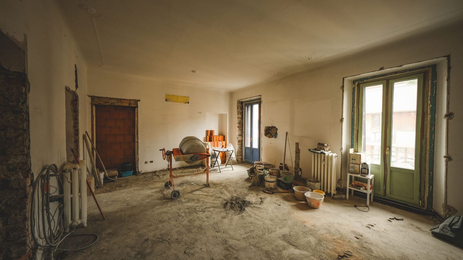 Pièce en rénovation avec bétonnière et seaux de plâtre
