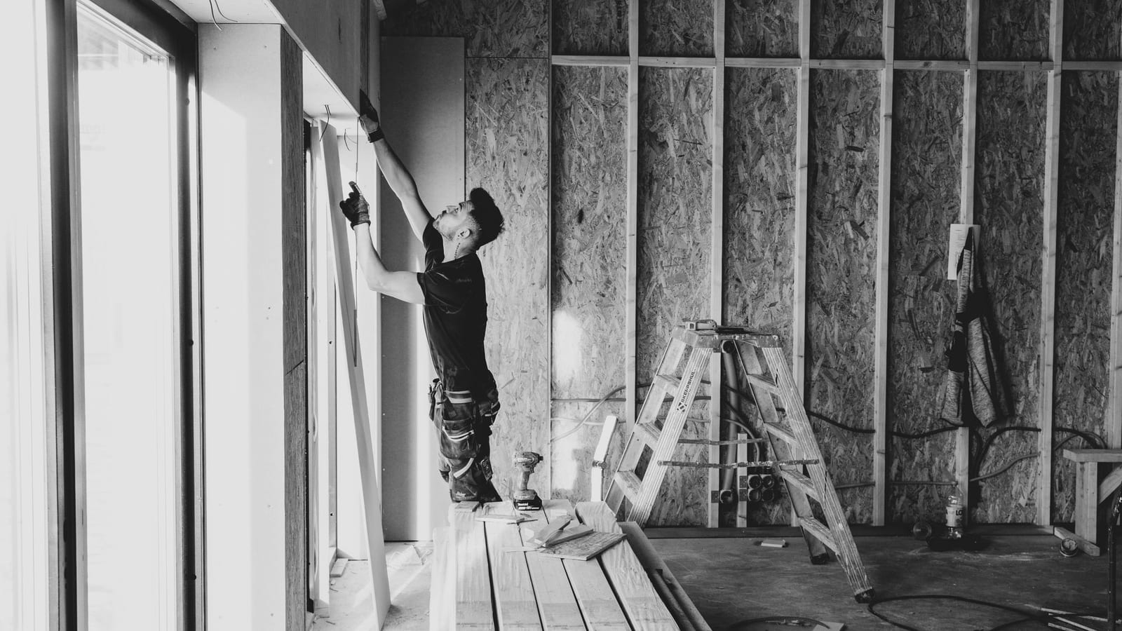 Worker fitting drywall in a room under construction